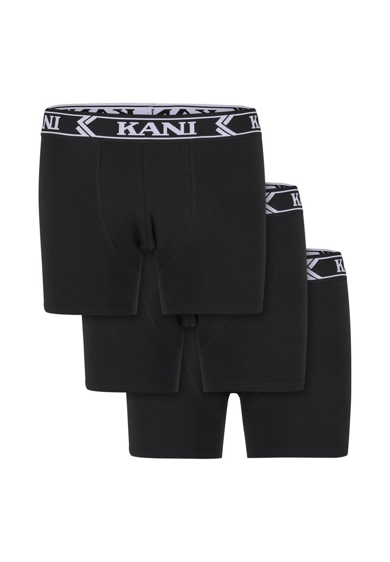 Trīs melni bokseršorti sakrauti, katram ar melnu un baltu jostu, kas rotāta ar "KANI" zīmolu.