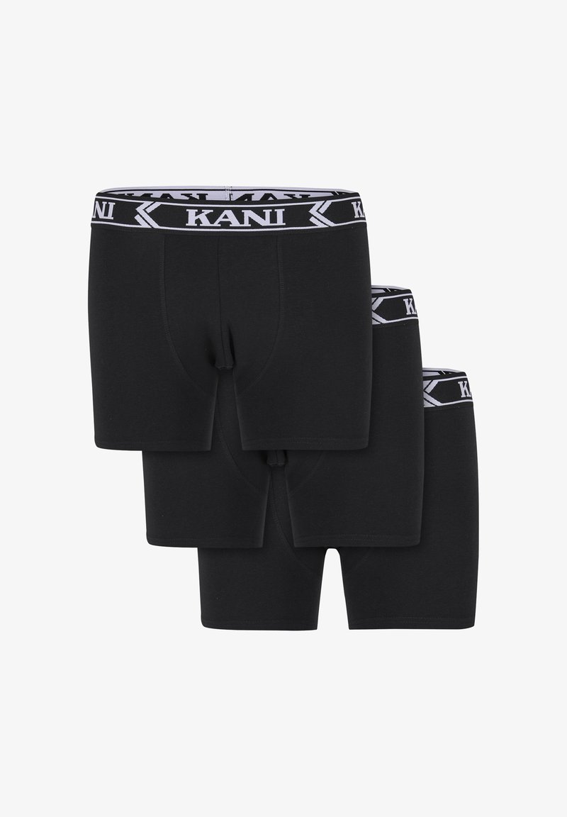 Trīs melni bokseršorti sakrauti, katram ar melnu un baltu jostu, kas rotāta ar "KANI" zīmolu.