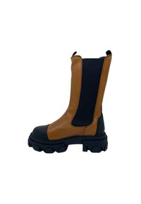 Bota de tornozelo em couro castanho com biqueira de borracha preta e sola robusta. Apresenta painéis laterais elásticos e abas para fácil calçar.