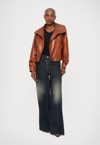 Chaqueta de cuero marrón corta con solapas anchas, combinada con jeans de tiro alto y pierna ancha de color azul con un acabado desgastado.