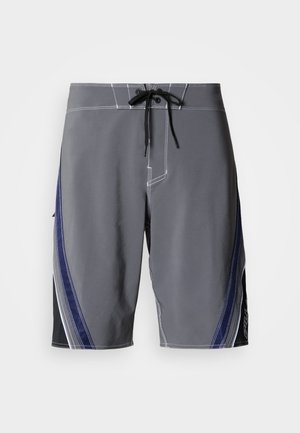 Sivé plavkové šortky s čiernym a námorníckym modrým bočným vzorom, s bielym prešívaním a šnúrkou v páse. Hladká textúra, dĺžka do kolien.