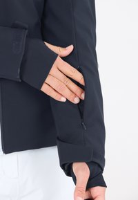 Marine softshell jakke har en lynlåslomme på ærmet og justerbare Velcro manchetter for en sikker pasform. Glat tekstur.