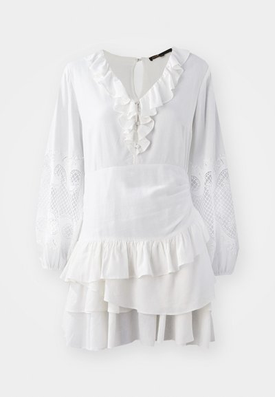 Valkoinen mekko, jossa on röyhelöreunus, pitkät ilmavat hihat, joissa on brodeeratut yksityiskohdat, ja kerroksellinen helma. Valmistettu kevyestä kankaasta.