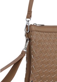 Brązowa pleciona skórzana torba o gładkiej fakturze, z metalowymi elementami w kolorze srebrnym. Regulowany pasek i zamek błyskawiczny, podkreślające szczegółowy wzór.