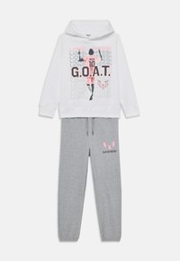 Biały hoodie z graficznym nadrukiem i ilustracją, zestawiony z szarymi dresami z różowym logo. Materiał bawełniany, luźny krój.
