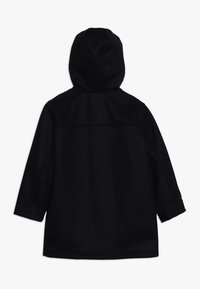 Cappotto nero con cappuccio in tessuto morbido, caratterizzato da un taglio dritto, maniche lunghe e un design posteriore semplice senza chiusure o dettagli visibili.