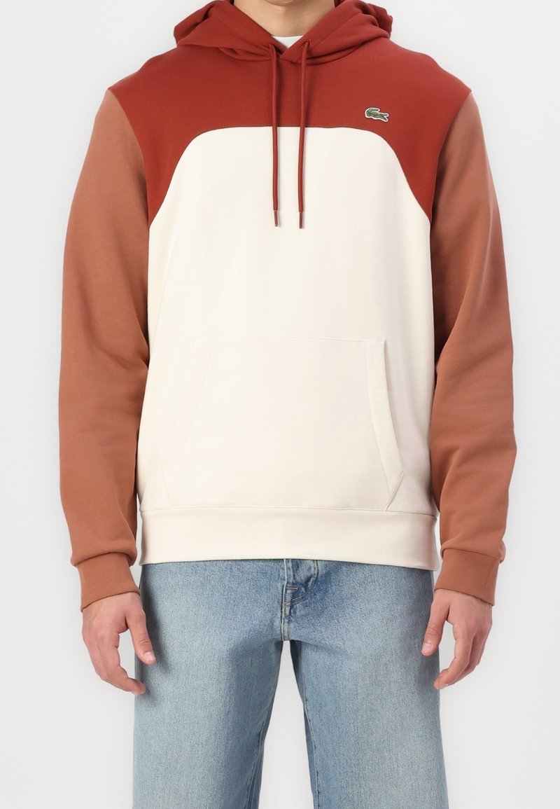 Sudadera con capucha que presenta un cuerpo color crema y mangas color burdeos. Confeccionada en tejido suave, incluye un bolsillo frontal y un pequeño logo en el pecho.