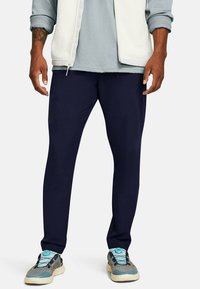 Pantalones deportivos en azul marino con un ajuste tapered, que presentan una textura suave, un branding sutil y detalles de costura curvada para mayor comodidad.