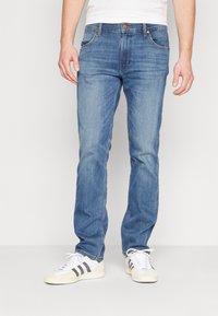 Jeans de denim albastru deschis, cu croială dreaptă, design cu cinci buzunare, cusături în contrast și o etichetă din piele maro pe talie.