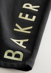Crni materijal s riječju "BAKER" u velikim, reflektirajućim, svijetlozelenim slovima. Tekstura tkanine je glatka s čistim završetkom.
