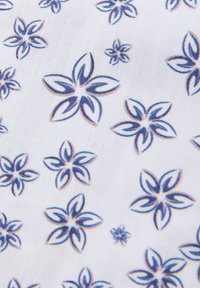 Materiał z białym tłem i powtarzającymi się niebieskimi wzorami kwiatów. Kwiaty mają kształt płatków z szczegółowymi konturami i różnymi rozmiarami.