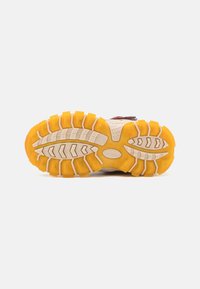 Semelle de chaussure de course en caoutchouc, avec une semelle extérieure jaune texturée et des rainures profondes, ainsi qu'un semelle intermédiaire plus légère pour une meilleure traction et stabilité.