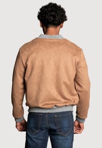 Veste bomber en daim marron avec un col et des poignets côtelés gris. Présente une texture lisse et une taille élastiquée. Vue de dos.