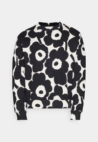 Svart og hvit genser med blomsterdesign som har store sorte blomster og hvite detaljer. Klassisk rund hals og ribbestrikkede mansjetter.
