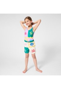 Πολύχρωμο μαγιό με σχέδια αστεία και κοχυλιών, σε ροζ και τιρκουάζ αποχρώσεις. Συνδυάζεται με μπεζ σορτς με ελαστική μέση.