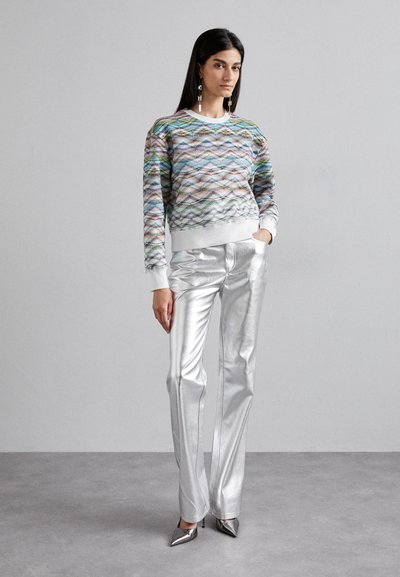 Πολύχρωμο υφαντό πουλόβερ με υφή και λευκούς μανικιών, σε συνδυασμό με μεταλλικές ασημί παντελόνες φαρδιάς γραμμής και μεταλλικά ψηλά τακούνια.