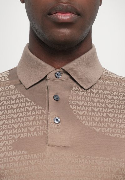Lys brun polo-skjorte med et teksturert mønster av logoen "Emporio Armani," med to mørke knapper og klassisk krage.