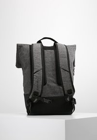 Zaino grigio e nero con un motivo a spina di pesce, dotato di spallacci imbottiti regolabili e design con apertura a rotolo per una chiusura sicura.