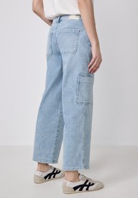 Jeans cargo bleu clair à larges jambes, dotés de deux poches arrière et d'une poche latérale. Fabriqués en tissu denim, avec une finition légèrement délavée.