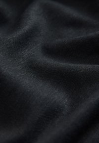 Crna tkanina glatke teksture, s diskretnim sjajem i tkanim uzorkom, prekrivena tako da se prikazuje njezina fleksibilnost i mekani nabori.