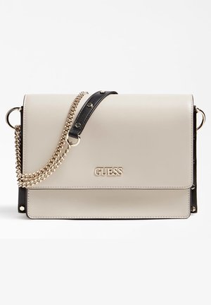 Sac à bandoulière Guess couleur crème avec chaîne dorée et détails en cuir noir sur fond uni.