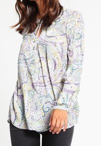 Blusa a maniche lunghe con un motivo paisley multicolore in viola, giallo e verde su uno sfondo chiaro, con scollatura rotonda.