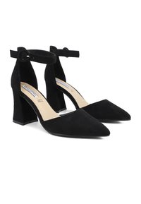 Scarpe con tacco a blocco in suede nero con punta affusolata e cinturini alla caviglia dotati di fibbia circolare. Superficie liscia e soletta beige.
