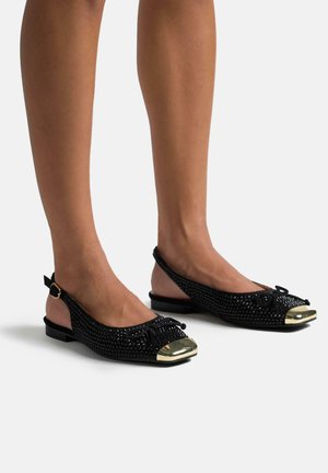Schwarze Slingback-Ballerinas mit einem geflochtenen Obermaterial und goldener Kappe. Mit einer Schleifendetails, flachem Absatz und einer glatten, strukturierten Oberfläche.