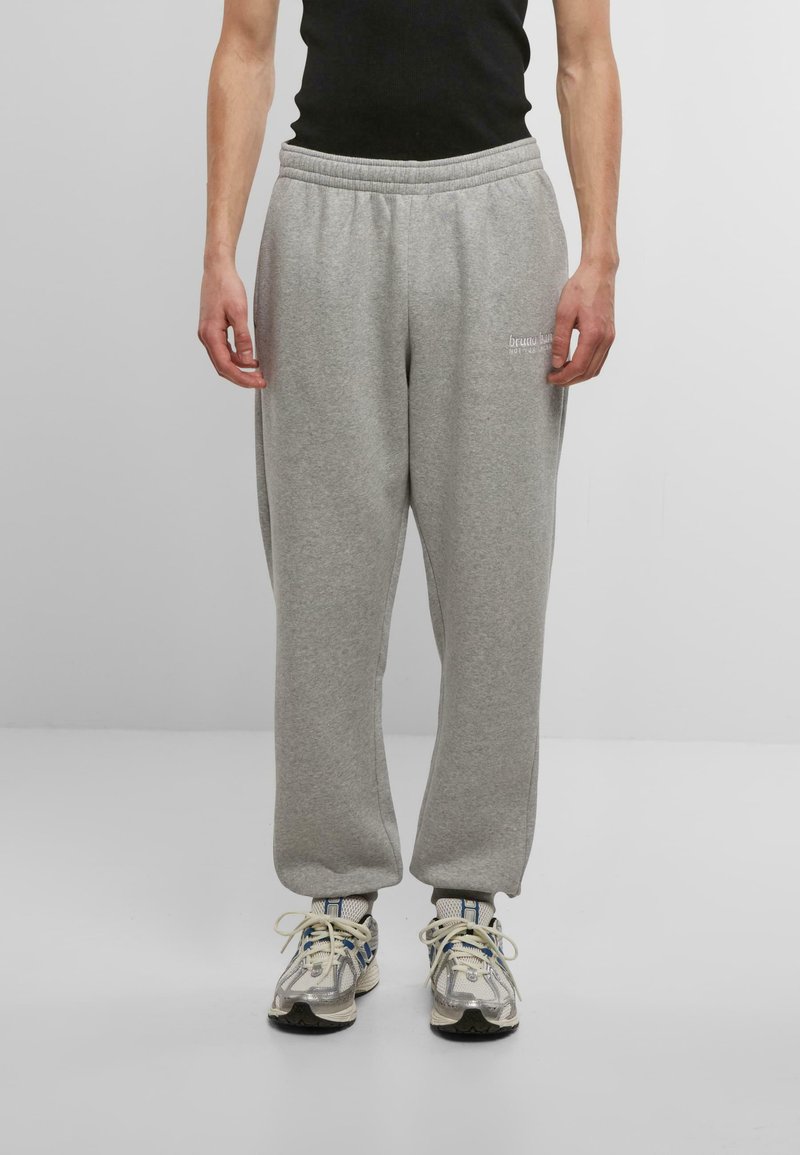Gray sweatpants made of soft fabric with an elastic waistband, featuring side pockets and minimal branding on the left thigh.
