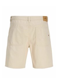 Short en denim beige avec deux poches arrière, passants pour ceinture et un petit patch en cuir marron sur la ceinture.