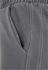 Les pantalons de survêtement gris sont dotés d'un tissu en maille texturée, d'une taille élastique et de poches latérales avec des coutures renforcées pour plus de durabilité.