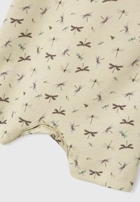 Tissu de coton jaune clair présentant un motif répétitif de libellules et de demoiselles en nuances de violet, bleu et marron, avec une texture douce.