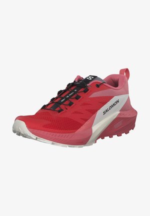 Zapatilla de trail running Salomon roja y rosa con cordones negros, suela blanca y dibujo texturizado, vista desde el lado frontal izquierdo.