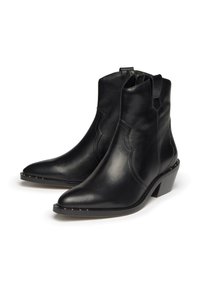 Botas de cuero negras hasta el tobillo con punta afilada, costuras decorativas, paneles elásticos en los lados y un tacón bajo apilado. Detalle de costura reforzada.