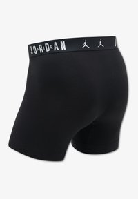 Black boxer shorts with a Jordan logo waistband. The fabric has a smooth texture and a fitted design, extending to mid-thigh.