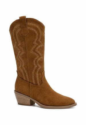 Bruine suède cowboylaars tot halverwege de kuit met decoratieve stiksels, aantreklipje, lage opgestapelde houten hak en spits toelopende neus naar rechts.