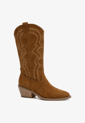 Brauner Veloursleder-Cowboystiefel bis zur Mitte der Wade mit dekorativer Naht, Zuglasche, niedrigem gestapeltem Holzabsatz und spitzer Schuhspitze nach rechts gerichtet.