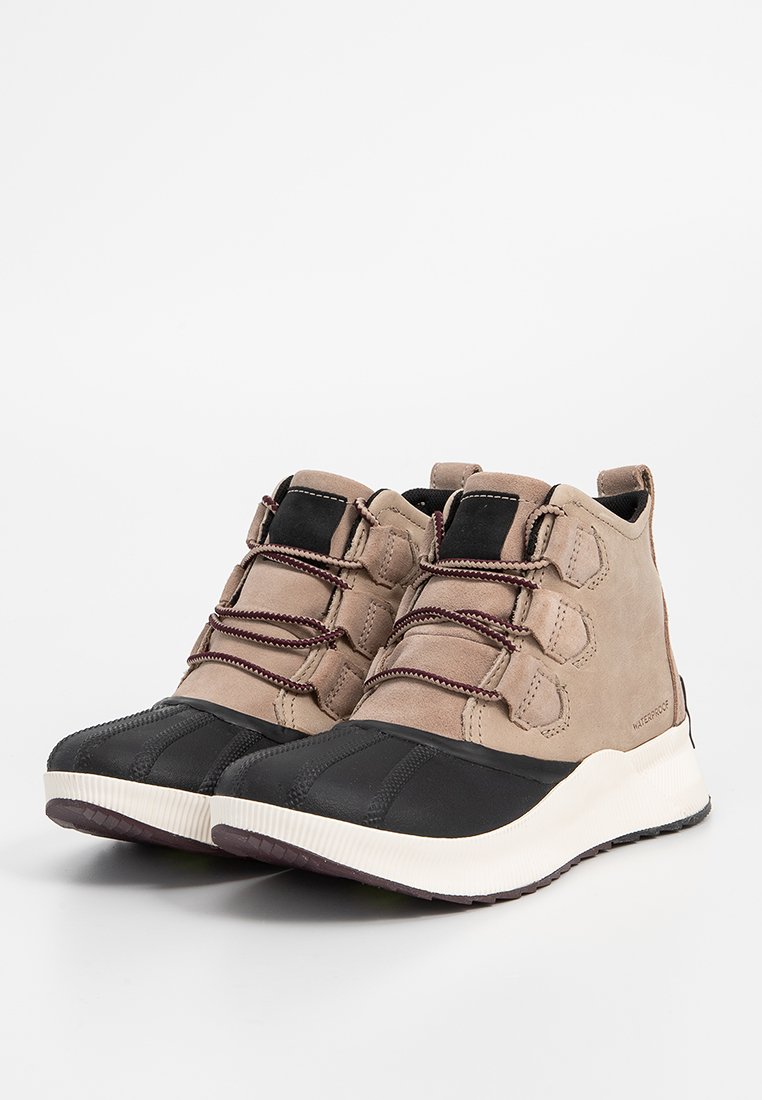 Beige Wildleder- und schwarze Gummisneaker mit einem High-Top-Design, elastischen Schnürsenkeln und strukturiertem Außensohle für besseren Halt.