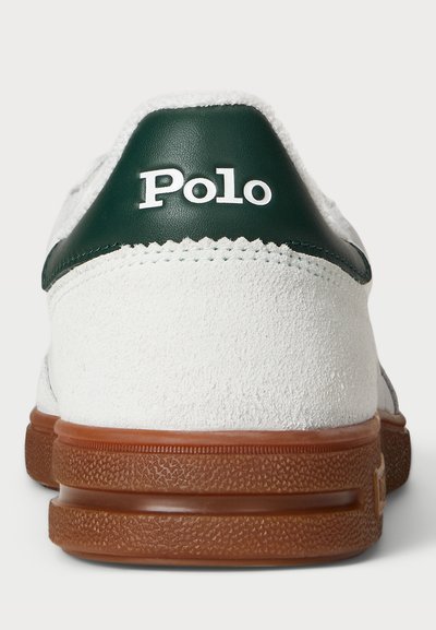Beli športni copat z zelenim usnjenim detajlom in "Polo" logotipom na peti. Ima teksturiran svetlo rjav gumijast podplat in gladko suknjo zgornjega dela.