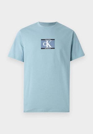 Light blue short-sleeve t-shirt in cotton material featuring a square graphic with "Calvin Klein" and "New York City" text, and a prominent "CK" logo.