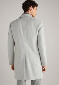 Abrigo gris claro con una textura suave, diseño de un solo botón, cuello con muesca y una abertura en la parte trasera. Cuenta con mangas largas y un corte entallado.