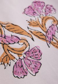 Rosa blommönster med bruna blad, dekorerad med paljetter på en vit bakgrund. Texturerad tyg som visar screentryckteknik.