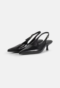 Černé kožené lodičky na pata s špičatou špičkou, texturovaným povrchem a nízkým stiletto podpatkem. Obsahují přezkovou zarážku pro nastavení.