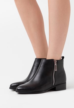 Černé kotníkové boty z hladké kůže s kulatou špičkou, nízkým blokovým podpatkem a bočním zipem se stříbrným zdobením.