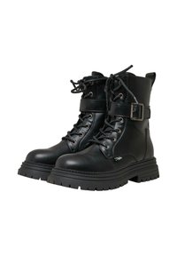 Botas de tobillo de cuero negro con suelas gruesas y con taco, parte delantera con cordones y correas con hebillas alrededor de los tobillos sobre un fondo blanco.