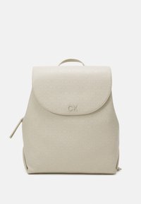 Beżowy skórzany plecak z zaokrągloną klapką, wytłaczanym wzorem logo, górnym uchwytem i bocznym zamkiem błyskawicznym. Gładka tekstura i minimalistyczny design.