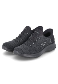 Schwarze Skechers Sportchuhe mit einem strukturierten Strick-Obermaterial, elastischen Schnürsenkeln und einer gepolsterten Sohle, die für Komfort und Flexibilität konzipiert sind.