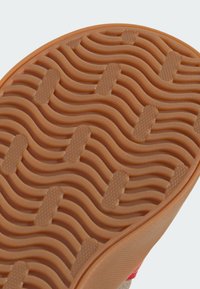 Gumená podrážka s vlnitým vzorom a vystúpenými bodkami. Farba je svetlohnedá. Textúra je hladká s jemným protišmykovým dizajnom.