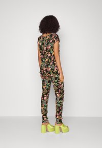 Floral-patterned outfit with short sleeves, black background, bright pink and green details, paired with chunky lime green platform shoes.