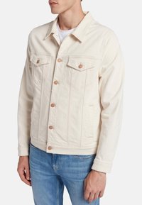 Giacca di jeans crema con colletto classico, tasche frontali e bottoni in tono rame. Tessuto strutturato con dettagli cuciti e vestibilità rilassata.